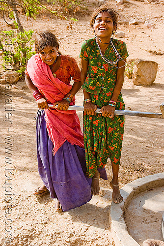 country girls pumping water with hand pump handle two Udaipur water pump