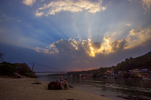 crepuscular rays at sunset on ganges river in rishikesh (india), beach, cloudy sky, crepuscular rays, ganga, ganges river, ram jhula, rishikesh, sun rays through clouds, sunset, suspension bridge