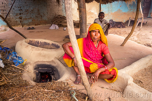 hindu woman sitting near mud stove, adobe floor, cross-legged, earthen floor, fireplace, indian woman, khoaja phool, kitchen, man, sari, sitting, village, wood stove, खोअजा फूल
