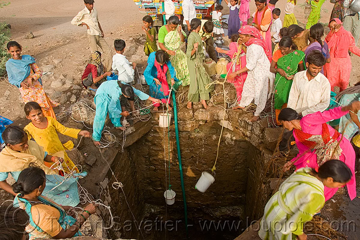 Women Scooping Water With Buckets At Village Water Well Ajanta India
