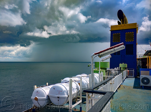 a tropical squall on the horizon - view from upper deck of ferryboat, clouds, deck, exterior, ferry, ferryboat, funnel, horizon, life boats, ocean, outside, sea, ship