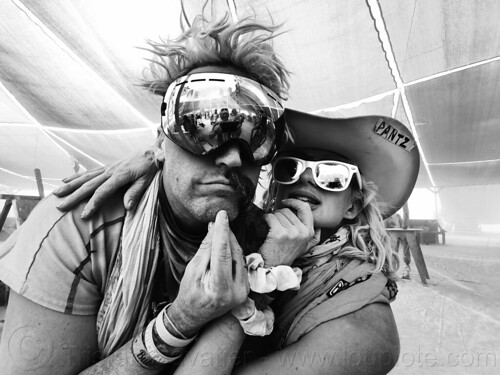 burning man - dusty couple in center camp cafe, dusty, goggles, half mustache, hat, man, sunglasses, woman