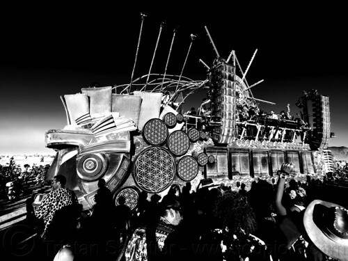 burning man - mayan warrior art car sunset party on the playa, burning man art cars, burning man at night, crowd, mayan warrior art car, mutant vehicles