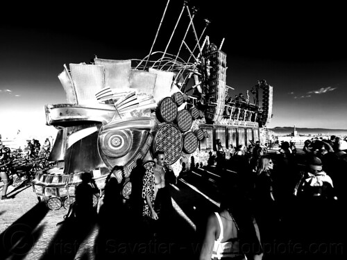 burning man - mayan warrior art car sunset party on the playa, burning man art cars, burning man at night, crowd, mayan warrior art car, mutant vehicles