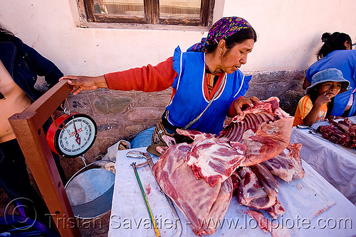 indigenous woman selling llama meat, argentina, butcher, llama meat, meat market, meat shop, merchant, noroeste argentino, quebrada de humahuaca, raw meat, street seller, tilcara, vendor, weigh scale, weighting scale, woman