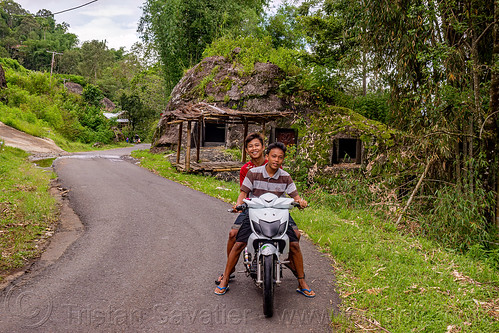 toraja kids on motorbike, with rock tombs in the back, burial site, cemetery, graves, graveyard, kids, kig, liang pak, motorcycle, road, rock tombs, tana toraja